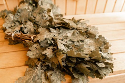 dry oak broom for a bath close-up. Wooden Finnish sauna interior. scoops and oaken besoms in steam bathroom.