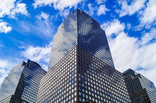 Office building close up with reflecting cloudy sky.