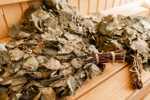 dry oak broom for a bath close-up. Wooden Finnish sauna interior. scoops and oaken besoms in steam bathroom.