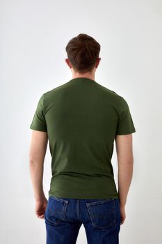 Back view unrecognizable male wearing jeans and casual t shirt standing on white background in studio