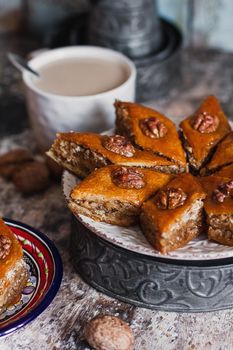 Assorted baklava. A Turkish ramadan arabic sweet dessert on a decorative plate, with coffee cup in the background. Middle eastern food baklava with nuts and honey syrup.