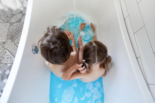 Close up kid legs in bathtub with full of clean blue water, bath tube with human legs in water