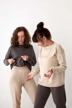 Middle aged and young women wearing casual homey pants and natural woolen sweatshirts standing against white background