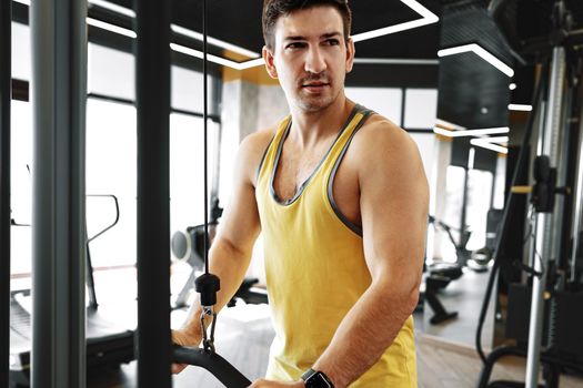 Young bodybuilder doing heavy weight exercise for biceps in a gym, close up