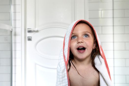 Charming nude girl with blue eyes and mouth opened in towel after washing routine in bathroom