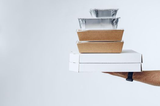 Courier hands giving packed food delivery close up against grey background