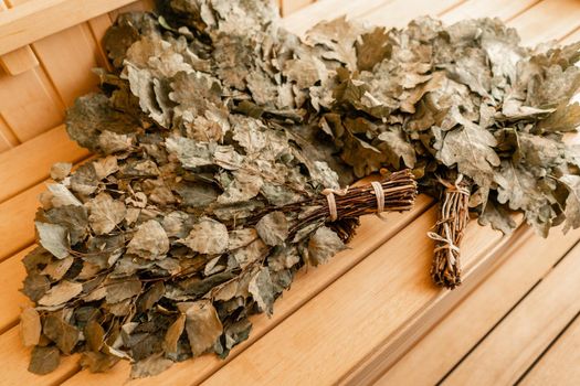 dry oak broom for a bath close-up. Wooden Finnish sauna interior. scoops and oaken besoms in steam bathroom.