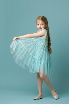 Beautiful little girl in an elegant dress holds her hands around the edges of the skirt.