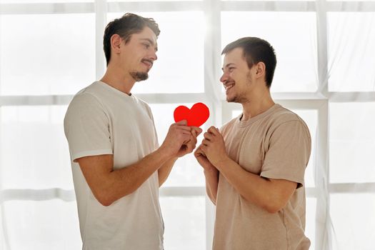 Gay couple celebrating valentine's day. A guy gives a valentine to man at home