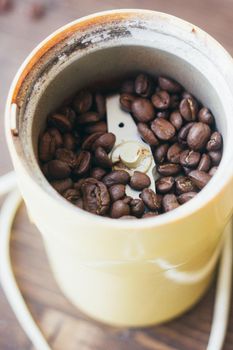 Electric coffee mill machine with coffee beans inside. Coffee grinder over the kitchen table