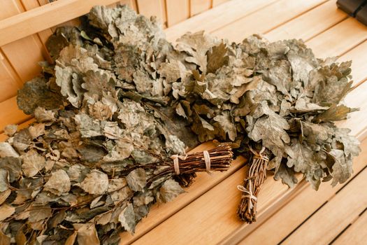 dry oak broom for a bath close-up. Wooden Finnish sauna interior. scoops and oaken besoms in steam bathroom.