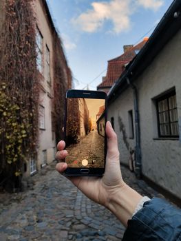 view of a small street of the old city through the smartphone screen on an autumn day. Riga, Latvia