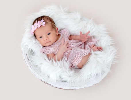 Lovely newborn girl with open eyes in beautiful dress