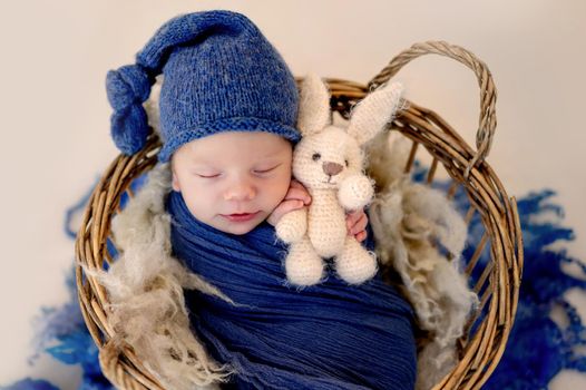 Lovely newborn with toy sleeping in basket