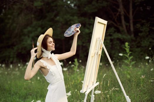 pretty woman artist paints a picture on nature landscape. High quality photo