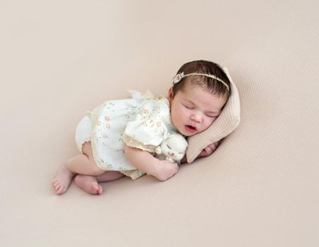 Nice newborn hugging toy sleeping on side on tiny pillow