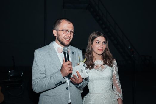 The bride and groom at the microphone party thank guests and parents.