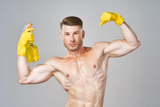 man in yellow rubber gloves with pumped muscles detergent cleaning. High quality photo