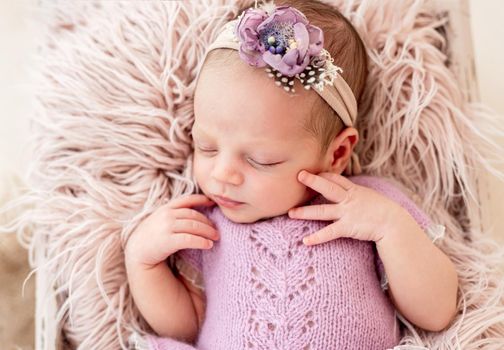 Sleeping newborn baby girl in a pink dress