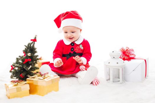 Santa baby girl with gift box and christmas decorations on a fur