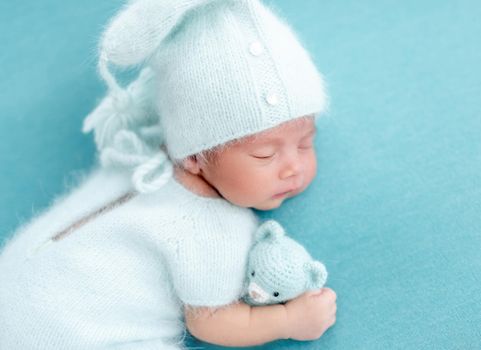 Cute sleeping newborn in knitted blue suit