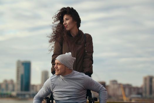 Portrait of a loving couple - beautiful woman with young disabled man on the hill overlooking the city, telephoto shot