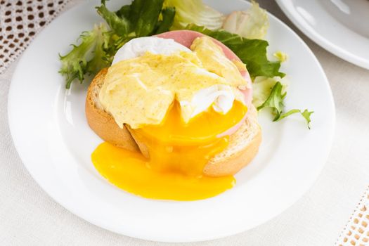 Eggs benedict close up on white plate, serving table