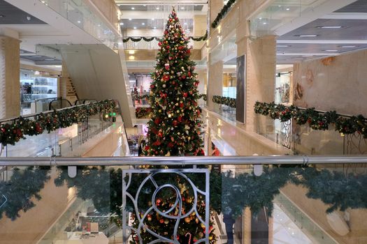 Interior of contemporary shopping mall with Christmas tree and decorations during winter holidays