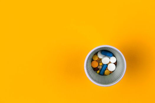 Medicine colorful pills or tablets of glass on yellow background