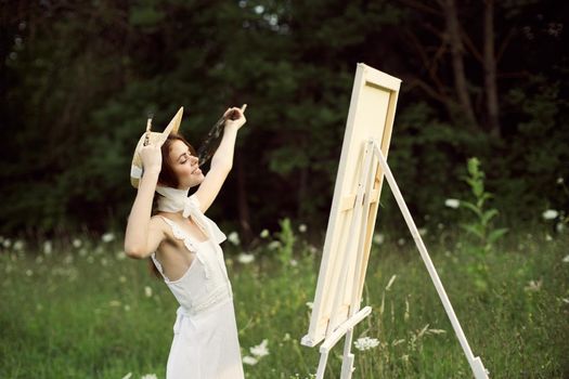 pretty woman artist paints a picture on nature landscape. High quality photo
