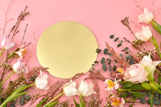 High angle of assorted blooming flowers and plants arranged on pink background with golden shiny round paper