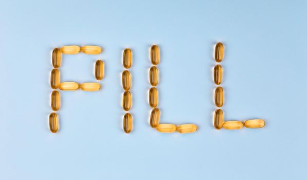 The word Pill is laid out with tablets. The word Pill is laid out with gel pills on a blue background with copy space for text