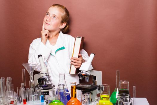 Thoughtful schoolgirl standing near blackboard in the laboratory classes in chemistry