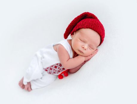 Cute newborn wearing ukrainian emboidered shirt and red hat