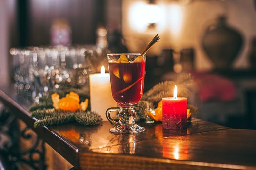 Red hot drink glintwein with spices, cinnamon, anise, fruits, brown sugar on an old wooden table. New Year and Christmas holidays concept. Mulled wine and glintwein