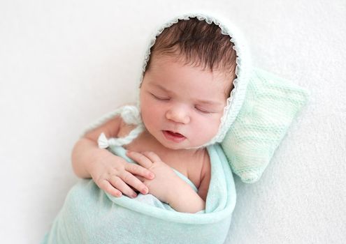 Cute newborn sleeping peacefully on tiny pillow