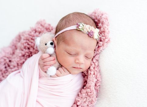 Sleeping newborn baby girl wrapped in white blanket