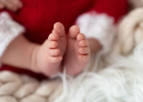 Bare feet of newborn in knitted santa suit
