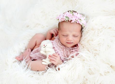 Sleeping newborn baby girl in a pink dress