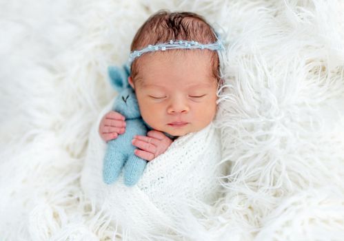 Cute newborn holding toy in tiny hands