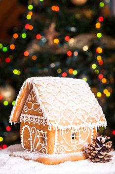 gingerbread house over defocused lights of Chrismtas decorated fir tree