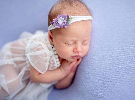 Cute newborn in lace dress sleeping on side