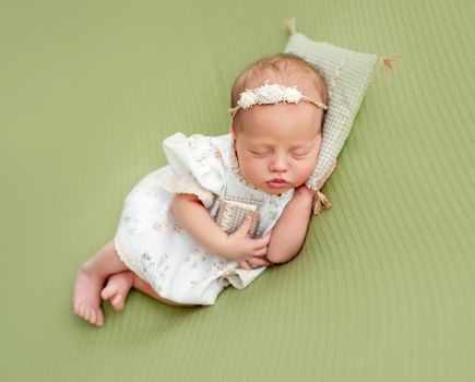 Charming newborn resting on tiny pillow holding small book