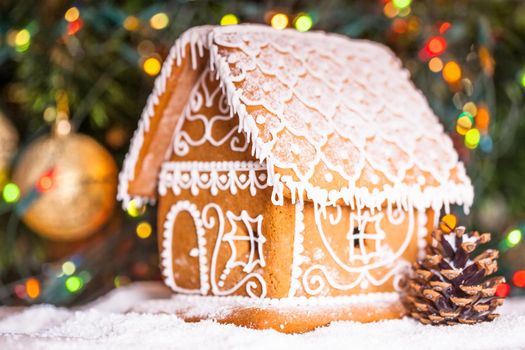 gingerbread house over defocused lights of Chrismtas decorated fir tree