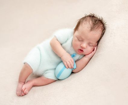 Cute asleep newborn holding easter egg