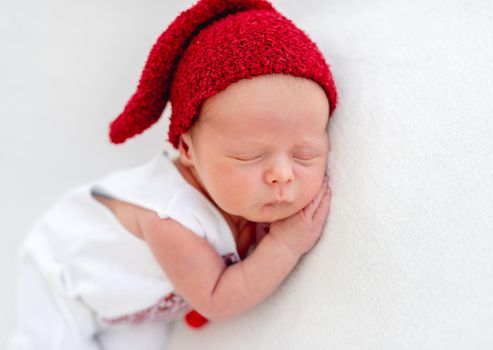 Cute newborn wearing ukrainian emboidered shirt and red hat