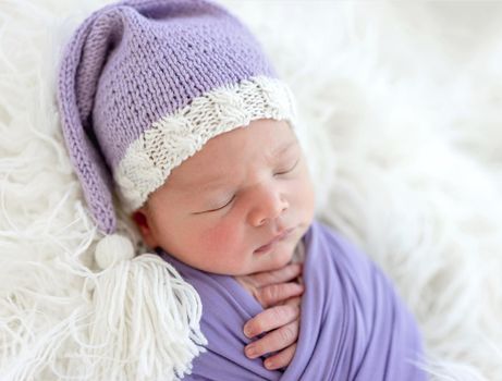 Cute newborn in knitted hat sleeping