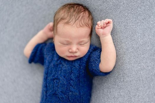 Charming newborn sleeping on back with hands up