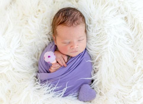 Lovely newborn sleeping with toy in tiny hands