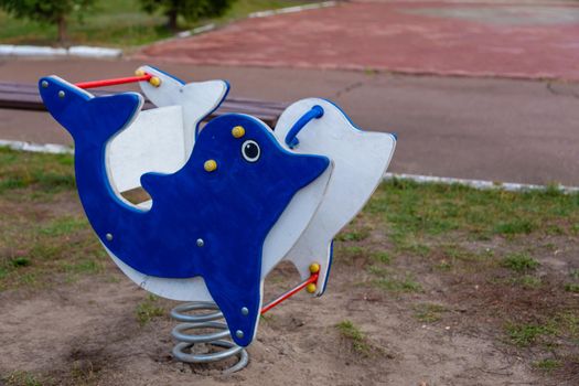 Children's swing at the playground. Cute dolphin and a regular swing in the background.